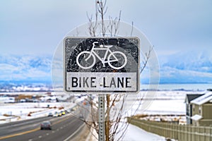 Bike Lane sign post in front of a tree and snow covered landscape in winter