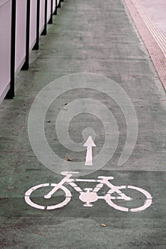 Bike lane symbol with a direction arrow on ground. Bicycle trail road sign on modern bridge for bike and cyclists in urban city.