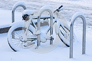 A bike left in a parking space with a thick layer of fresh snow