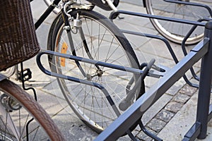 Bike locked securely via u-lock in bicycle parking area. Front right side view of front wheel. Security, stolen bike