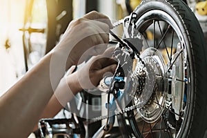 Bike mechanic repairs folding bicycle in Workshop. adjust Rear Derailleur ,cassette sprocket . Bicycle Maintenance and Repair