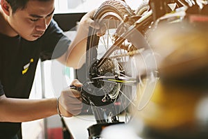 Bike mechanic repairs folding bicycle in Workshop. adjust Rear Derailleur ,Maintenance and repair concept