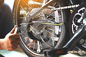 Bike mechanic repairs folding bicycle in Workshop. adjust Rear Derailleur ,Maintenance and repair concept