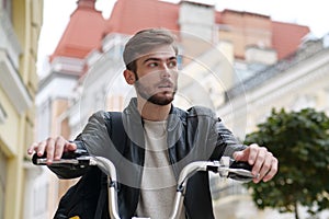 Bike messenger with backpack sits on bicycle and looks around