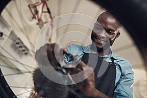 This bike really needed a new part. Low angle shot of a handsome young man standing alone in his shop and repairing a