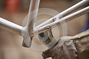 Bike renovation: man using a wire brush over a bike frame to remove the paint