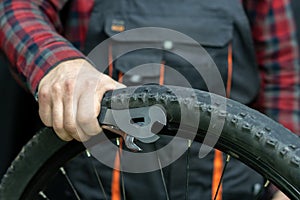 bike repair. Bike mechanic in the workshop. A mechanic holds tools and a bicycle wheel in his hand. Hands of the master and keys