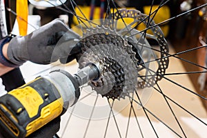 The bike repairman installs the cassette by electric drill to the bike