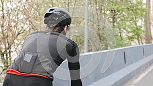 Bike rider wearing black and red outfit on bicycle in the park. Back close up follow shot. Cycling concept.