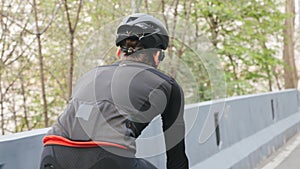 Bike rider wearing black and red outfit on bicycle in the park. Back close up follow shot. Cycling concept. Slow motion