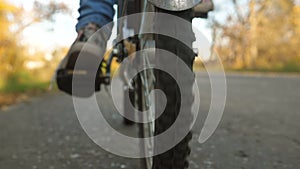 Bike rides on asphalt road. legs of girl pushing the bicycle pedals. wheel with tread rides, close-up