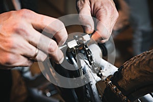 Bike service: mechanic serviceman repairman installing assembling or adjusting bicycle gear on wheel in workshop