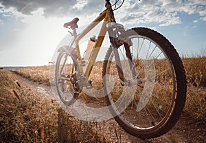 Bike silhouette at the sunset dirt road in the countryside