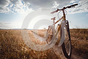 Bike silhouette at the sunset dirt road in the countryside