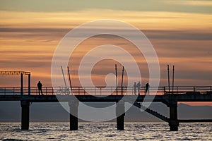 Bike, singles and a couple`s silhouettes on the pier