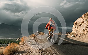 Bike tourist rides on Himalaya mountain road on way to buddist monastery