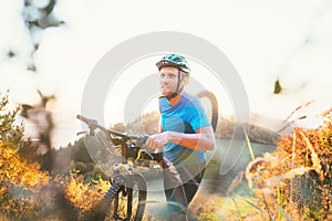 Cyclo-cross competition member Man mountain biker carrying his bike up on hill top