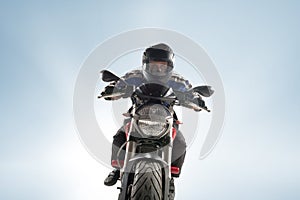 Biker in black jacket and helmet sitting on his sportive bike on blue background