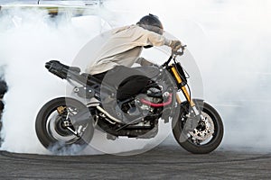 Biker burning tire and creating smoke on bike in motion