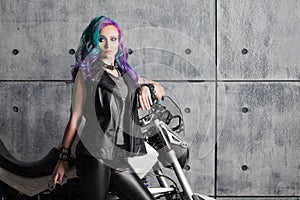 Biker chick in front of motorcycle. Beautiful and pert young woman in leather clothes