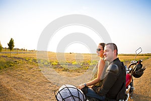 Biker couple on the country road against the sky