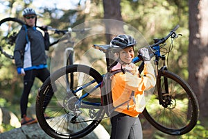 Biker couple holding their mountain bike and walking in forest