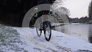 Biker cycles on canal towpath after winter snowfall