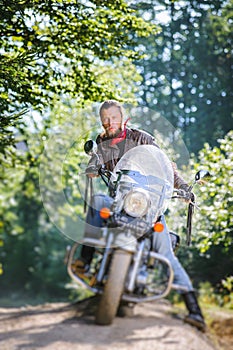 Biker driving his cruiser motorcycle on road in the forest