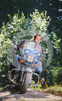 Biker driving his cruiser motorcycle on road in the forest