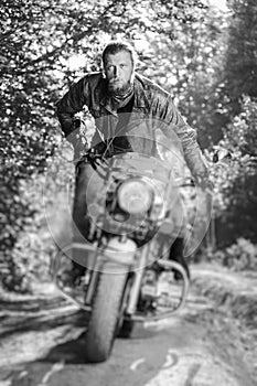 Biker driving his cruiser motorcycle on road in the forest