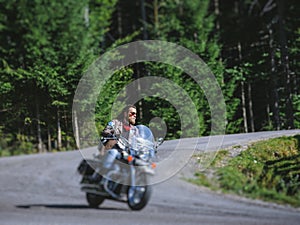 Biker driving his cruiser motorcycle on road in the forest