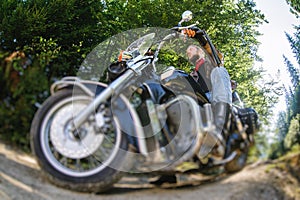 Biker driving his cruiser motorcycle on road in the forest