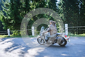 Biker driving his cruiser motorcycle on road in the forest