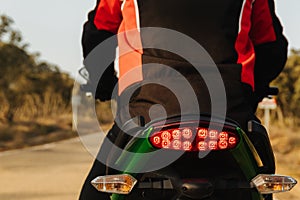 Biker driving his motorcycle in a traffic jam, braking for road safety. red brake light on.