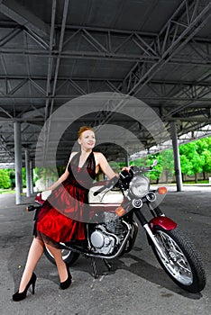 Biker girl in dress on a motorcycle over the