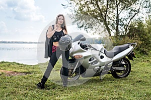 Biker girl holding leather jacket near motorcycle outside