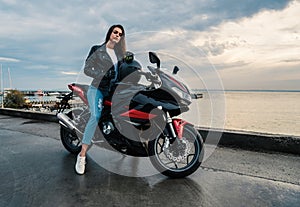Biker girl in a leather jacket on a black and red color motorcycle