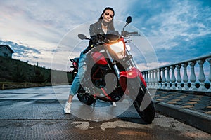 Biker girl in a leather jacket on a black and red color motorcycle