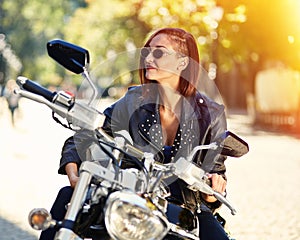 Biker girl in a leather jacket on a motorcycle