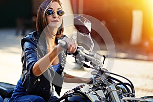 Biker girl in a leather jacket on a motorcycle