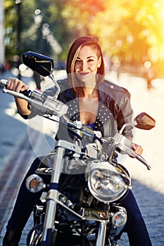 Biker girl in a leather jacket on a motorcycle