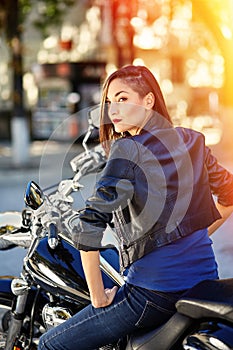 Biker girl in a leather jacket on a motorcycle