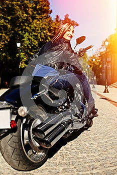 Biker girl in a leather jacket on a motorcycle