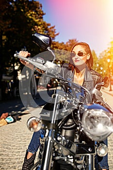 Biker girl in a leather jacket on a motorcycle