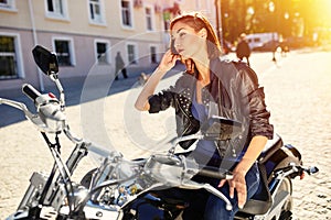 Biker girl in a leather jacket on a motorcycle