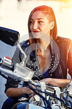 Biker girl in a leather jacket on a motorcycle