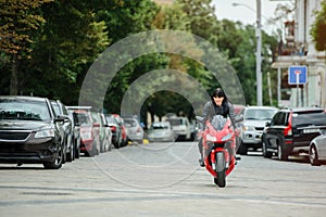 A biker girl in a leather jacket on a motorcycle rides in the city