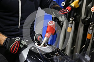 Biker hand holds a fuel filling gun in a motorcycle tank