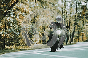 Biker In Helmet Is Riding On Highway In A Forest.