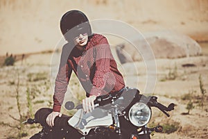 Biker with helmet start a vintage custom motorcycle. Outdoor lifestyle toned portrait